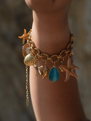 Χειροποίητο βραχιόλι σε χρυσή απόχρωση, διακοσμημένο με ατσάλινα στοιχεία εμπνευσμένα από τη θάλασσα: αστερίες, κοχύλια και σταγόνες. Οι χρωματιστές ημιπολύτιμες πέτρες προσθέτουν ζωντάνια και καλοκαιρινή ενέργεια, ενώ η στιβαρή αλυσίδα προσφέρει άνετη εφαρμογή και διάρκεια στον χρόνο.