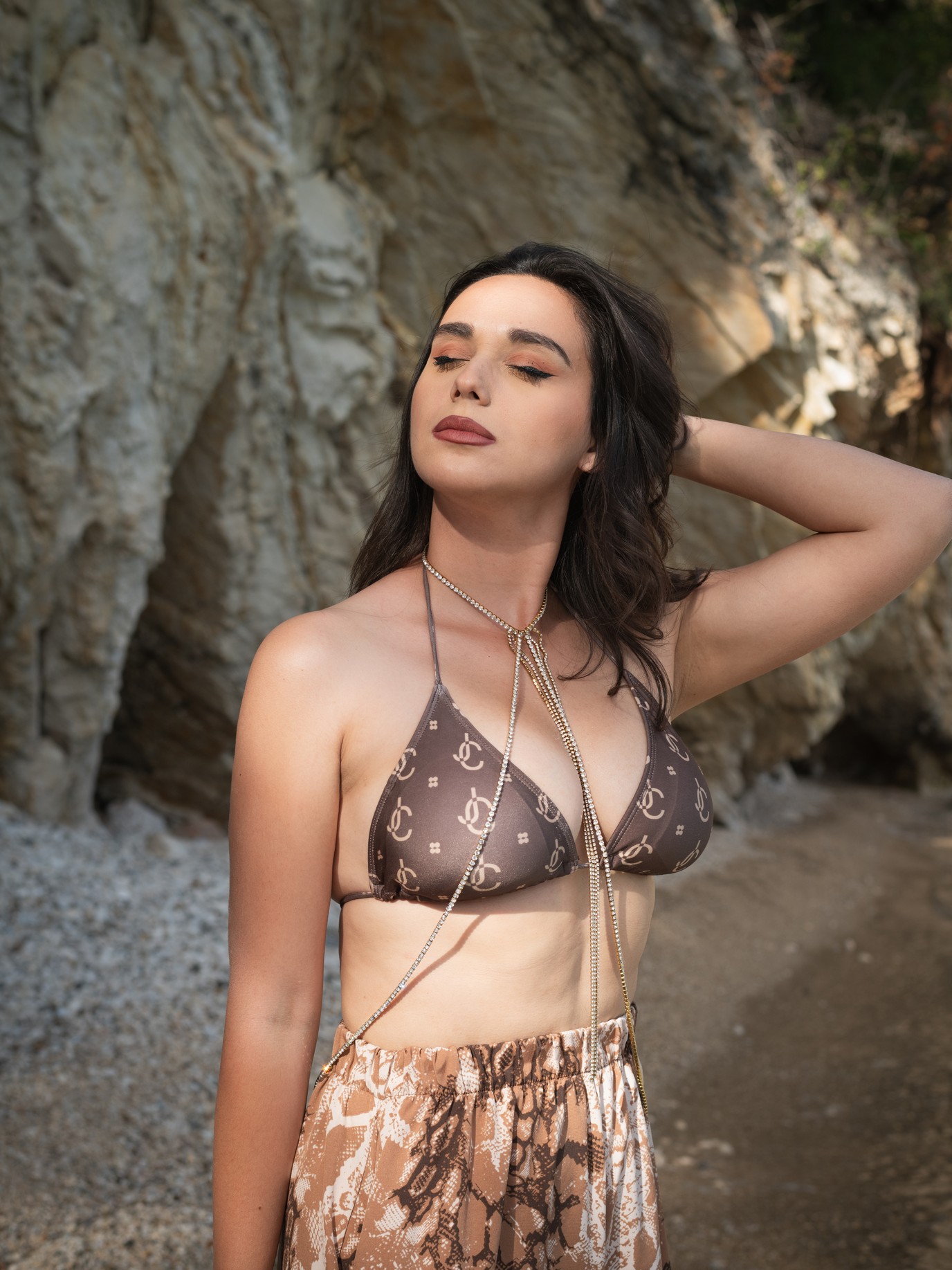 Κομψό ολόσωμο κολιέ από επιχρυσωμένο ατσάλι. Το λεπτό του δέσιμο αγκαλιάζει τον λαιμό και καταλήγει σε κάθετη διχάλα που ακολουθεί τη γραμμή του ντεκολτέ, δημιουργώντας ένα διακριτικά σαγηνευτικό αποτέλεσμα.