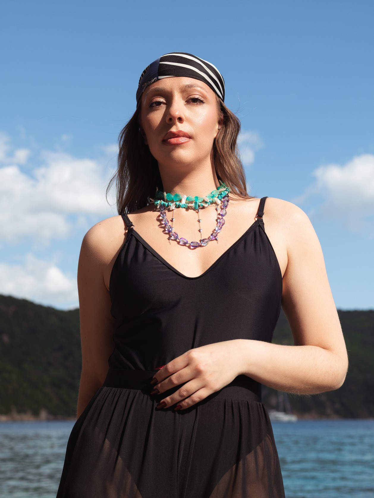 Εντυπωσιακό, διπλό κολιέ που παίζει με το φως και την κίνηση. Η βασική γραμμή αποτελείται από μωβ ιριδίζοντες κρυστάλλους σε σχήμα σταγόνας, που λαμπυρίζουν σε κάθε κίνηση, ενώ η δεύτερη γραμμή στολίζεται με λεπτή αλυσίδα και μεταλλικούς κώνους από αιματίτη για μοντέρνο edge αποτέλεσμα.