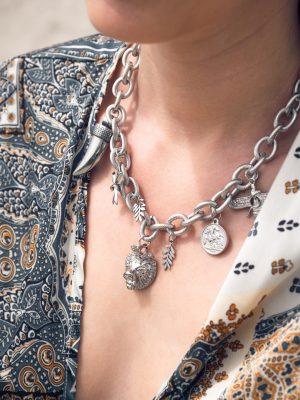 Επιβλητικό statement κολιέ με εντυπωσιακή αλυσίδα από ανοξείδωτο ατσάλι σε ασημί τόνο. Το σχέδιο κοσμείται με μοναδικά στοιχεία: κεφάλι λιονταριού, δόντι, φύλλα και αρχαιοελληνικά νομίσματα που αποπνέουν δύναμη, ιστορία και στυλ. Ένα κόσμημα με bold χαρακτήρα για εμφανίσεις που δεν περνούν απαρατήρητες.