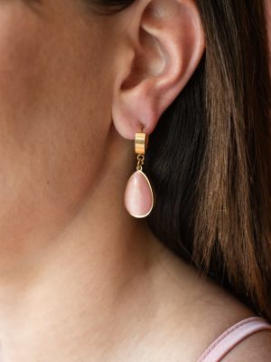Ένα σκουλαρίκι σε σχήμα δάκρυ, με φίνα ροζ πέτρα και χρυσό πλαίσιο που αποπνέει φινέτσα.