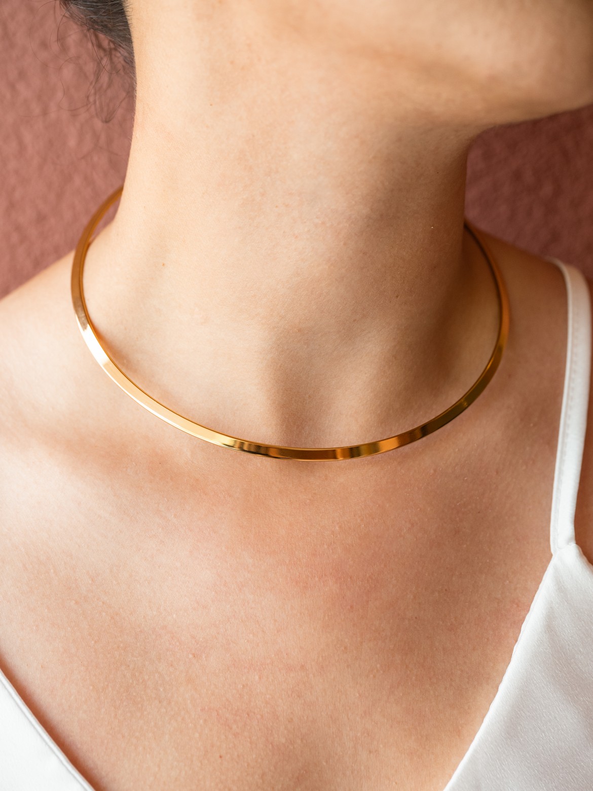 Minimal λαιμαριά με λεία, καθρέφτινη επιφάνεια και σταθερή φόρμα που αγκαλιάζει απαλά τον λαιμό.
