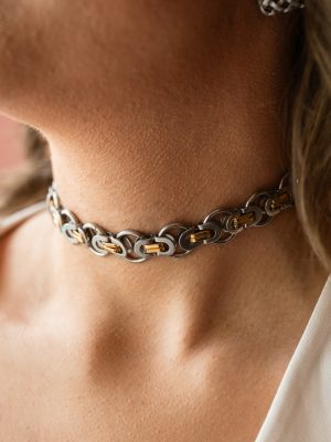 Η εντυπωσιακή του σχεδίαση από πυκνούς μεταλλικούς κρίκους και μηχανικά στοιχεία δημιουργεί ένα δυναμικό, unisex look που ξεχωρίζει.