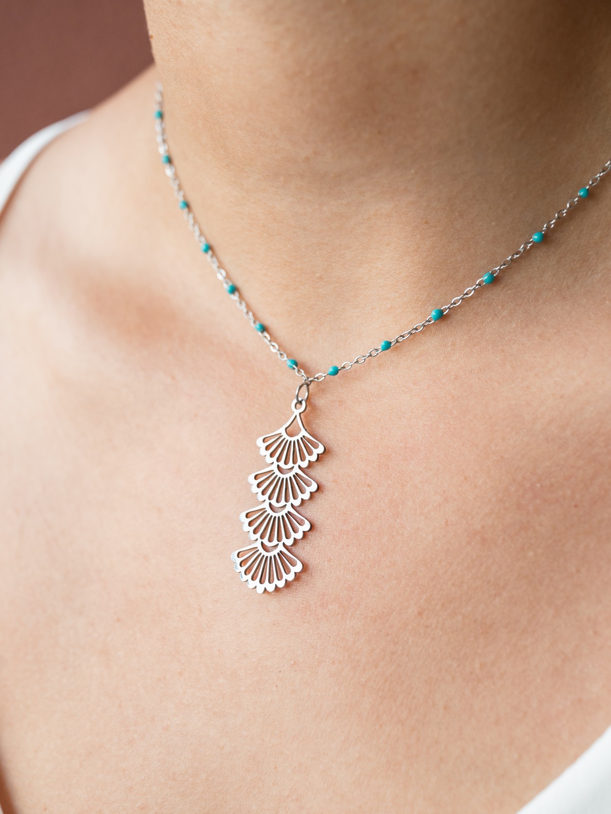 Ανάλαφρο και ρομαντικό κολιέ. Από λεπτή αλυσίδα με μικρές τιρκουάζ χάντρες που αγκαλιάζουν όμορφα τον λαιμό. Με κρεμαστό στοιχείο σε σχήμα βεντάλια.